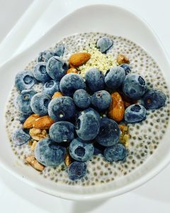 A bowl of chia pudding, topped with nuts, blueberries and hemp hearts